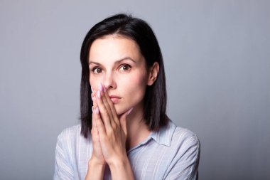 Mor gömlekli esmer bir kadın elini yüzüne dayadı.