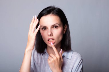 Kadın elleriyle yüzüne dokunuyor, gri stüdyo geçmişi var.