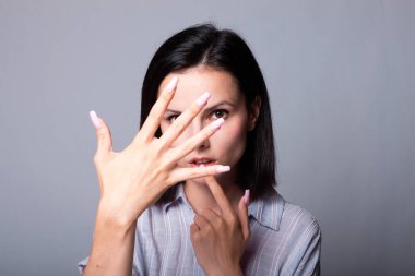 Kadın ellerini gösteriyor, gri stüdyo geçmişi var.