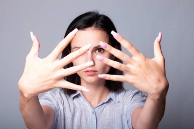 Kadın ellerini gösteriyor, gri stüdyo geçmişi var.