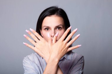 Kadın ellerini gösteriyor, gri stüdyo geçmişi var.