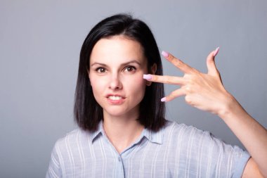 Kadın ellerini gösteriyor, gri stüdyo geçmişi var.