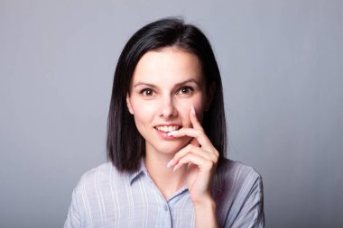 Kadın elleriyle yüzüne dokunuyor, gri stüdyo geçmişi var.