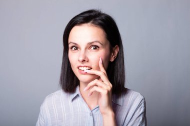 Kadın elleriyle yüzüne dokunuyor, gri stüdyo geçmişi var.