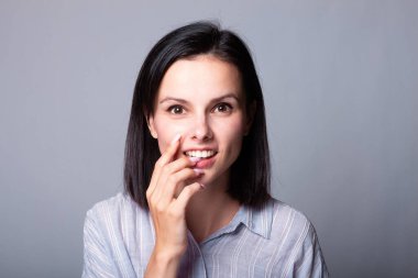 Kadın elleriyle yüzüne dokunuyor, gri stüdyo geçmişi var.