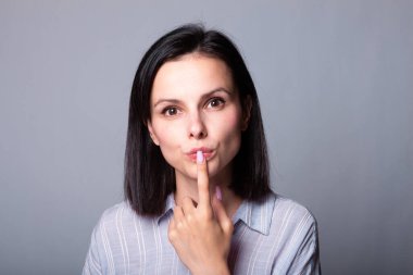 Kadın elleriyle yüzüne dokunuyor, gri stüdyo geçmişi var.