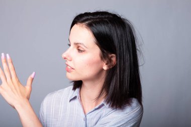 Kadın tırnaklarını gösteriyor, gri stüdyo geçmişi var.