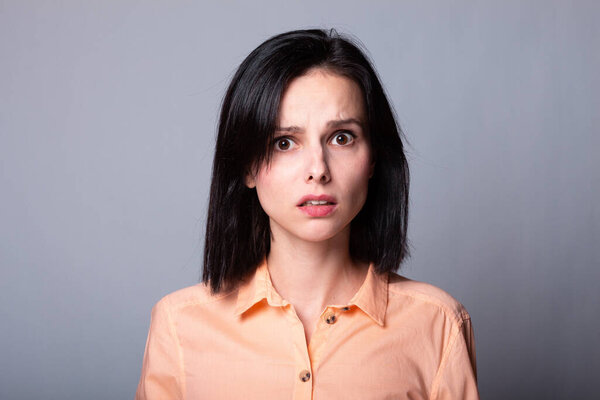 emotional woman in orange shirt, gray background