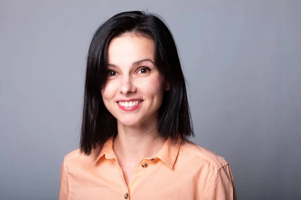 stock image emotional woman in orange shirt, gray background