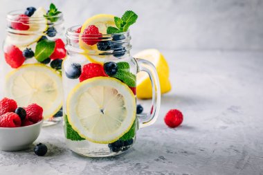 Limon dilimi, ahududu, yaban mersini ve nane ile infüzyon detoks su. Buz soğuk yaz kokteyl veya mason cam limonata