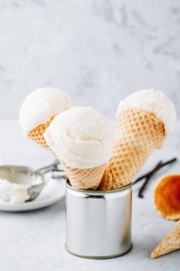 Ev yapımı vanilyalı dondurma kaşık gri arka plan üzerinde gözleme koni içinde