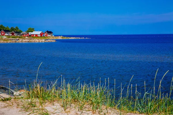 Red wooden houses on the lake or sea coast. Fishing village in rural Finland