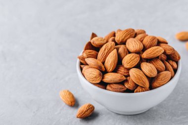 Tüm çiğ badem kase gri arka plan üzerinde. Kopya alanı