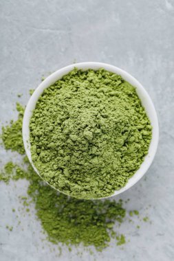 Matcha yeşil çay tozu gri taş zemin üzerine beyaz kase. Üstten görünüm. 