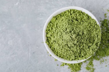 Matcha yeşil çay tozu gri taş zemin üzerine beyaz kase. Üstten görünüm. 