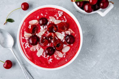 Sağlıklı kahvaltı kase. Kırmızı Kiraz smoothie taze çilek, badem pul ve Hindistan cevizi cips ile. 