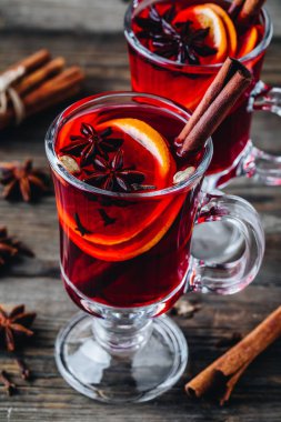 Baharatlar ve turuncu cam ahşap rustik arka plan üzerinde kırmızı şarap mulled. Ev yapımı Noel içki.