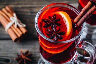 Baharatlar ve turuncu cam ahşap rustik arka plan üzerinde kırmızı şarap mulled. Ev yapımı Noel içki.