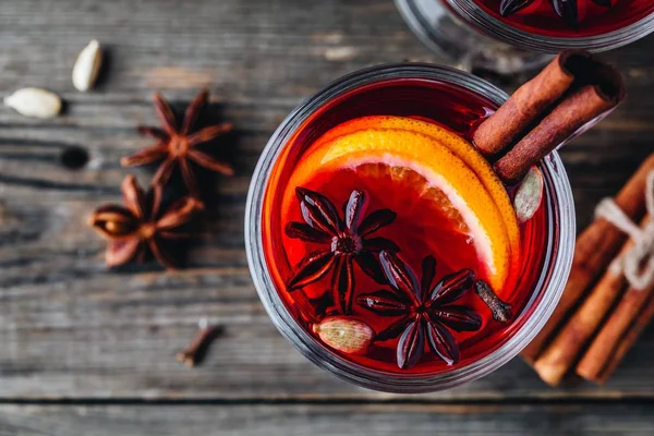 Baharatlar ve turuncu cam ahşap rustik arka plan üzerinde kırmızı şarap mulled. Ev yapımı Noel içki.