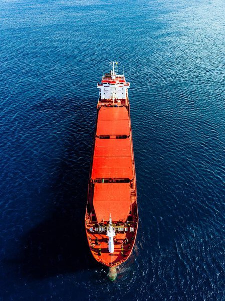 Aerial view of general cargo ship in blue sea in Italy. View from above of red empty container ship in the sea.
