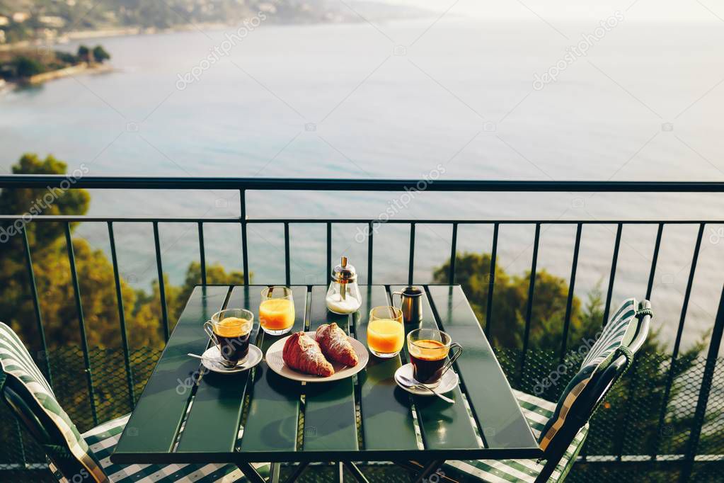 Delicious breakfast with coffee, pastry, and orange juice served on the balcony with sea view in Italy.