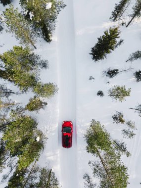 Finlandiya, Lapland ülkede yol üzerinde beyaz kar kış orman içinden araba kırmızı araba hava görünümünü. Drone üzerinden üstten görünüm