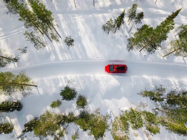 Finlandiya, Lapland ülkede yol üzerinde beyaz kar kış orman içinden araba kırmızı araba hava görünümünü. Drone üzerinden üstten görünüm