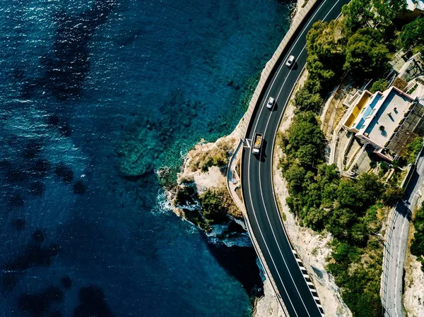 Vista aérea de la carretera a lo largo de la montaña y el océano o el mar . — Foto de Stock