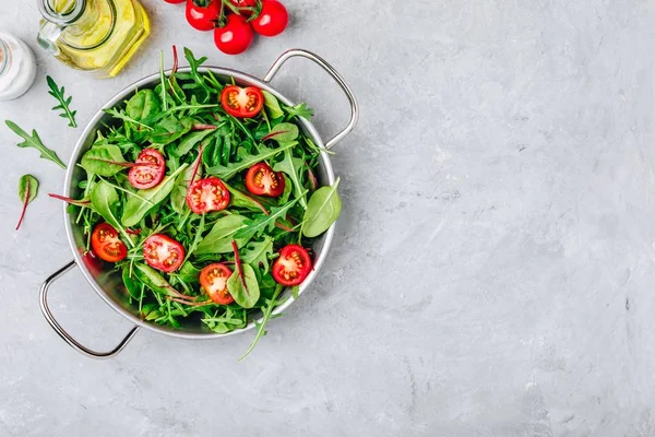 Insalata fresca con foglie verdi di rucola, lattuga, spinaci, barbabietole e pomodoro su fondo grigio . — Foto Stock