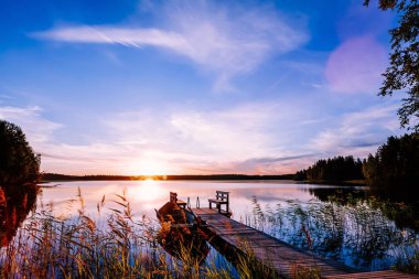 Finlandiya'da bir göl günbatımı balıkçı teknesi ile ahşap iskele