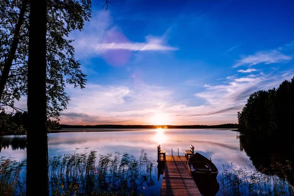 Masse en bois avec bateau de pêche au coucher du soleil sur un lac en Finlande — Photo