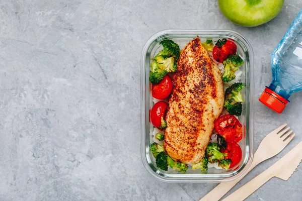 Grilled chicken meal prep containers with rice, broccoli and tomatoes.