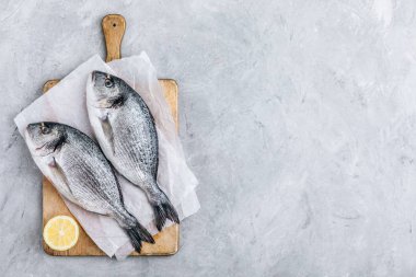 Baharatlı taze çiğ dorado balığı. Kesme tahtasında pişirme veya ızgara için malzemeler.
