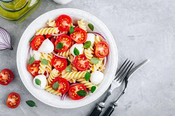 Italiaanse Pasta Salade met tomaten, mozzarella kaas, rode ui en basilicum. Top View. — Stockfoto
