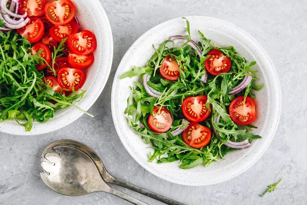 Healthy Green Fresh Arugula Salad Bowl with Tomatoes and Red Onions. Top view — Stock Photo, Image