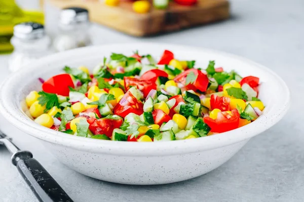 Свежий летний кукурузный салат с помидорами, огурцами, красным луком и петрушкой . — стоковое фото