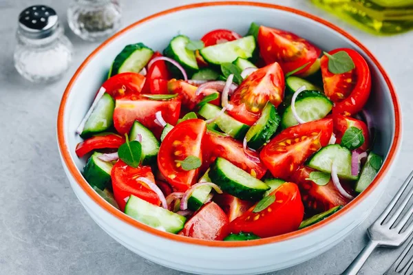 Świeża sałatka letnia miska z pomidorami, ogórkami, czerwoną cebulą, bazylią i opatrunkiem oliwy. — Zdjęcie stockowe