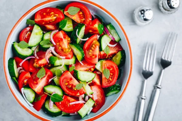 Fresh summer salad bowl with tomatoes, cucumbers, red onions, basil and olive oil dressing. — Stock Photo, Image