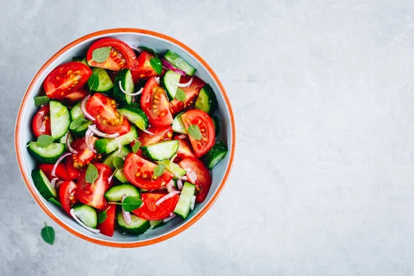 Fresh summer salad bowl with tomatoes, cucumbers, red onions, basil and olive oil dressing. — Stock Photo, Image