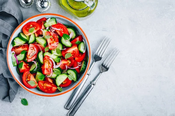Fresh summer salad bowl with tomatoes, cucumbers, red onions, basil and olive oil dressing. — Stock Photo, Image