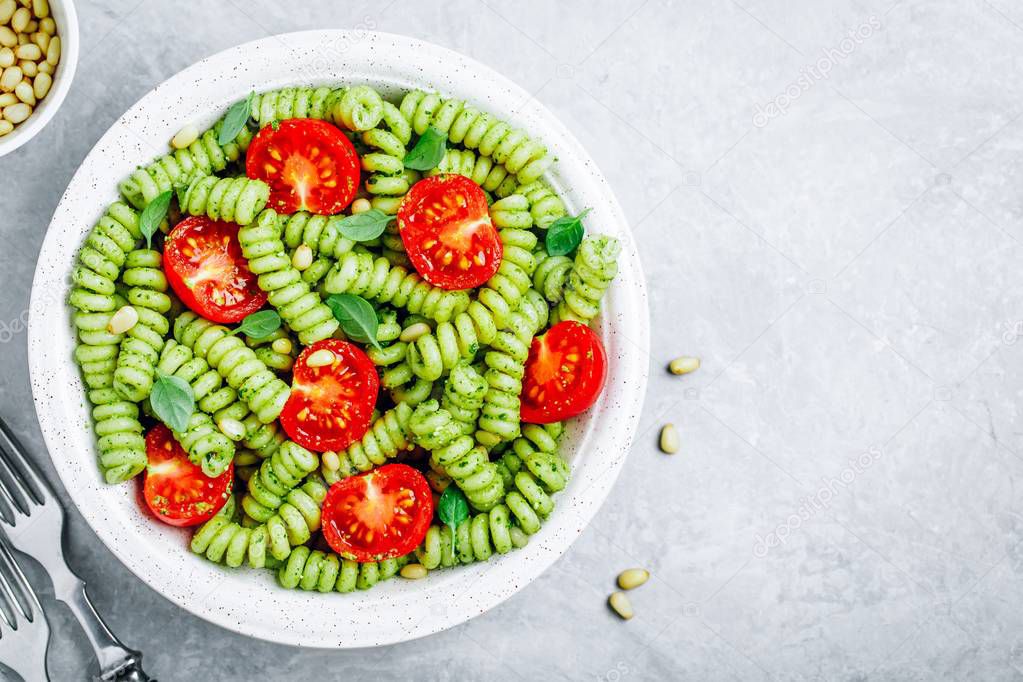 Fusilli pasta with basil pesto sauce , tomatoes and pine nuts. 