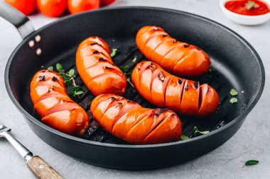 Dökme demir tavada ızgara sosisler. 