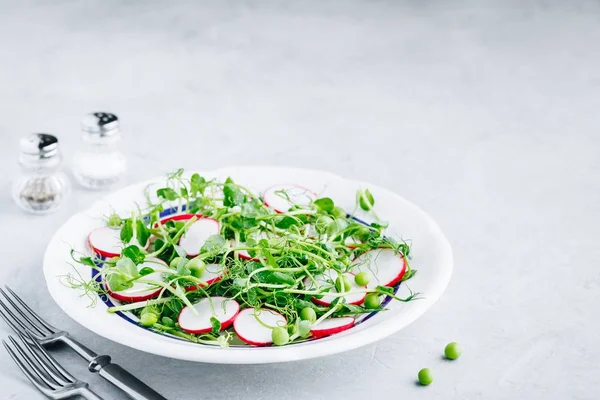 Fresh green pea shoots salad with radishes. — Stock Photo, Image