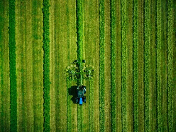 Luftaufnahme eines Traktors beim Mähen eines grünen Feldes in Finnland. — Stockfoto