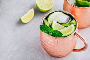 Gri taş arka plan üzerinde kireç ve nane ile bakır fincan Moskova katır buz soğuk kokteyl