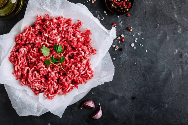 Raw ground minced meat and seasonings on dark background — Stock Photo, Image