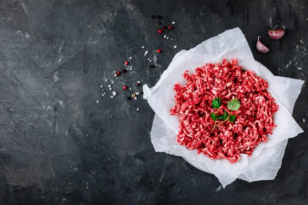 Raw ground minced meat and seasonings on dark background — Stock Photo, Image
