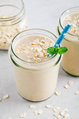 Bir taş arka planda cam Mason kavanozlarda muz yulaf Smoothie veya milkshake