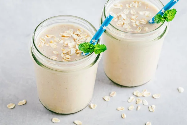 Batido de avena o batido de plátano en frascos de vidrio sobre un fondo de piedra —  Fotos de Stock