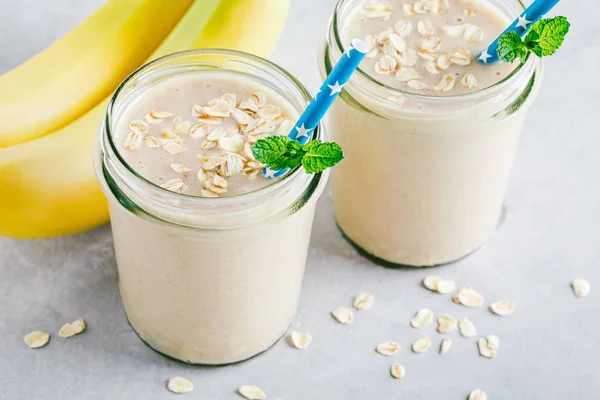 Batido de avena o batido de plátano en frascos de vidrio sobre un fondo de piedra —  Fotos de Stock